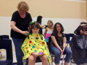 From left to right Lynn Goutouski of The Barber Shop cleaning up Courtney Lanktree's hair after she cut off 10” and raised $60, seated next to Courtney is Breanna Conley waiting to get her hair cleaned up after cutting off 9” and raising $250