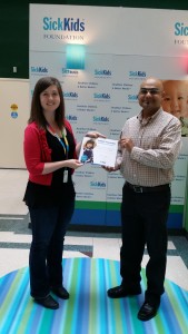 Brianne Fodey, events coordinator for SickKids presents Sanjay with a certification of appreciation for his hard work.